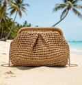 Clutch intrecciata in rafia con catena dorata su spiaggia tropicale